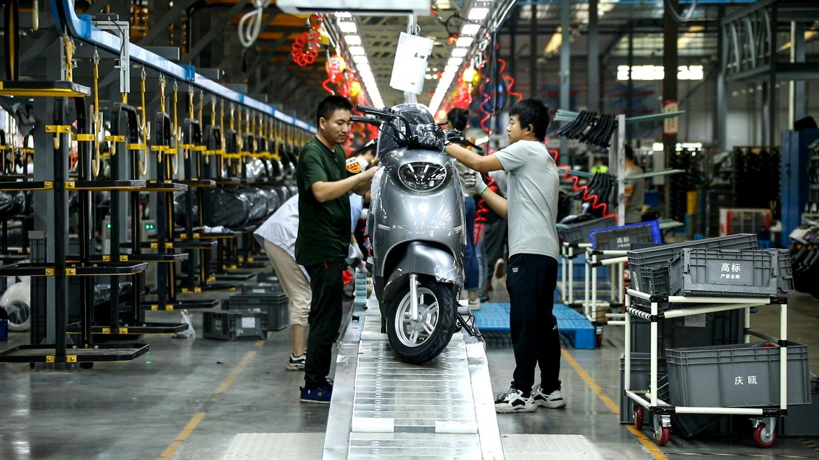 重庆爱玛车业科技有限公司，工人正在组装生产线上的电动摩托车.jpg