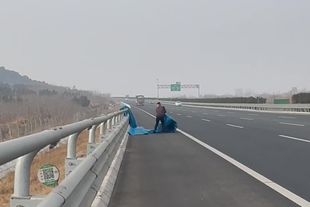 这个“熊人”又要做好事 高速快车道上掉落雨棚布 热心大哥停车后将其捡到路边