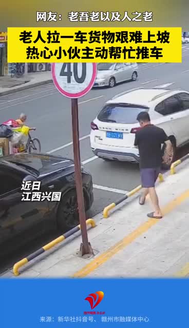 老人推着满载货物的三轮车爬坡，热心小伙主动帮忙推车